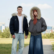 Two people wearing winter jackets and hats in a tiled hallway.