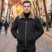 A man wearing a dark gray winter jacket with a thick brown faux-fur collar, layered over a black turtleneck.
