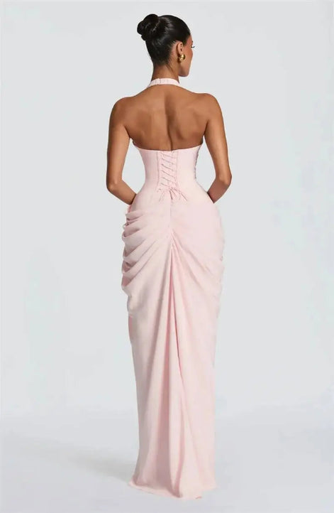 A woman viewed from the back wearing a pale blush pink strapless gown with a corset-style back and gathered skirt, 