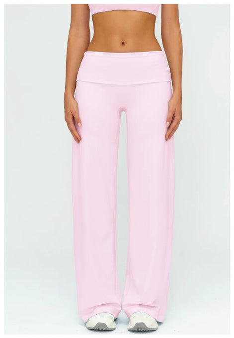 A model wearing light pink wide-leg athletic pants and a matching pink sports bra, shown from the waist down against a light gray studio background.