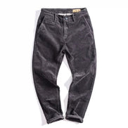 A pair of dark gray corduroy pants laid flat on a white background.
