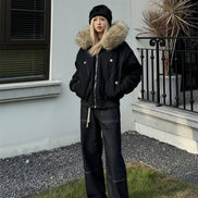 Person wearing a black coat with a fur-lined hood outdoors.