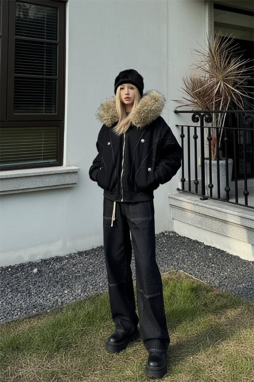 Person wearing a black coat with a fur-lined hood outdoors.