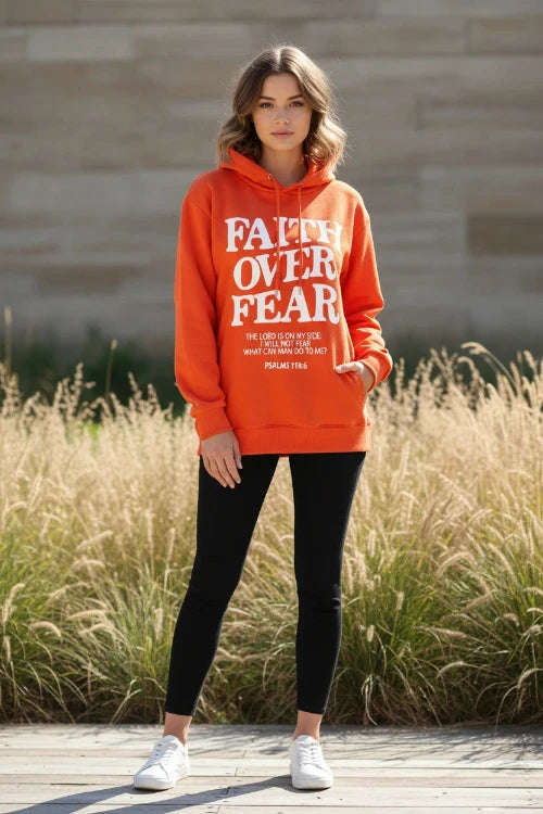 Orange hoodie with 'Faith Over Fear' text on a wooden surface