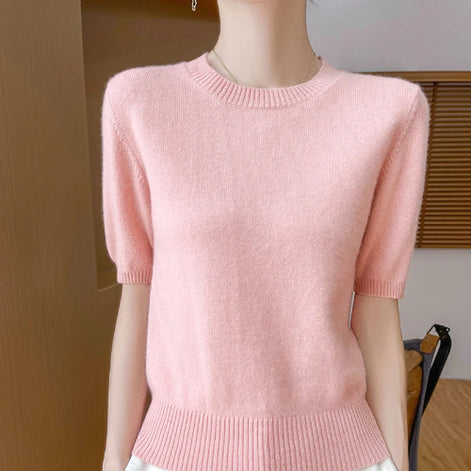 A light pink short-sleeve knit sweater with a crew neck and ribbed cuffs, shown on a mannequin torso in an indoor setting.