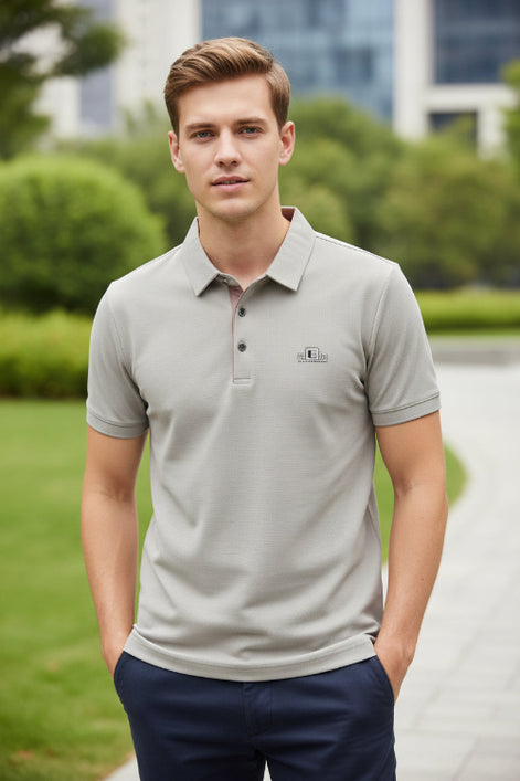 Light gray shirt with a brand logo on a hanger and being held by a hand.
