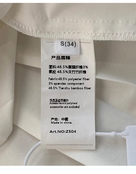 A close-up of a white fabric garment showing a sewn-in product tag with Chinese and English text including 'S(34)', material composition, and 'Made in China'.