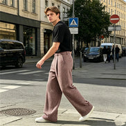 Herringbone wide-leg pants worn by a man crossing a street