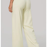 A person shown from the back wearing high-waisted, wide-leg pants in a pale cream or light butter color,