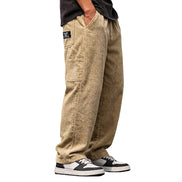 A person shown from the waist down wearing loose-fitting corduroy pants in a light tan/khaki color, paired with black and white sneakers, against a plain white background.