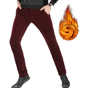 A person wearing slim burgundy corduroy pants with hands in pockets, shown from the waist down on a white background.