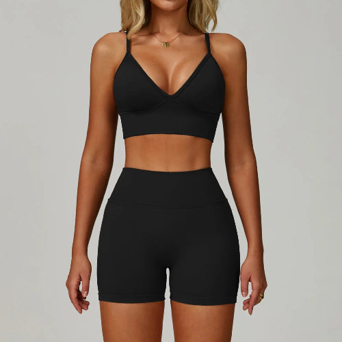 Person wearing a black sports bra and high-waisted shorts on a gray background