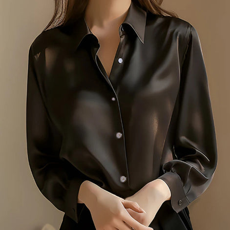Black satin button-down shirt worn by a model with hands clasped, shown from the front.