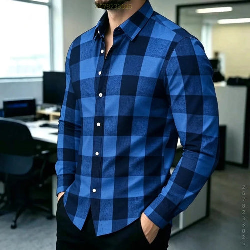 A man wearing a long-sleeve button-up shirt with a bold blue and navy buffalo plaid pattern, standing in an office environment.