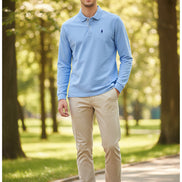 Light blue long-sleeve polo shirt with a small logo on a rack with other shirts.
