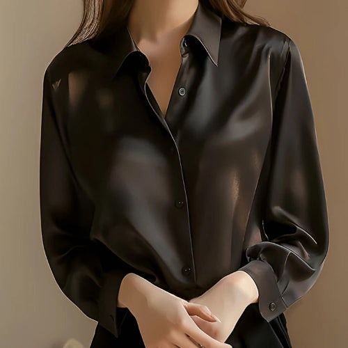 Black satin button-down shirt worn by a model with hands clasped, shown from the front.