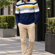 A man wearing a long-sleeve polo shirt with horizontal stripes in navy blue, gray, white, and yellow, paired with beige pants.
