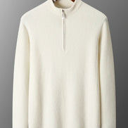 White sweater with a quarter zip on a hanger against a gray background