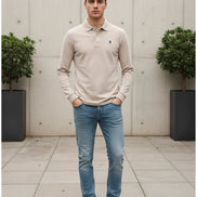 Beige long-sleeve polo shirt with a brand logo on a clothing rack.