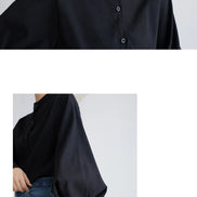 Black shirt worn by a person on a plain background