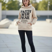 Beige hoodie with 'Faith Over Fear' text on a white surface