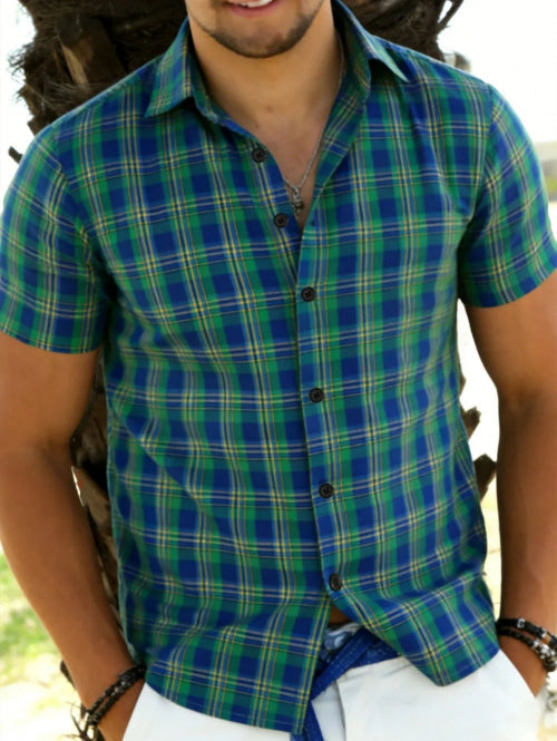 Person wearing a green and blue plaid shirt with a blurred background