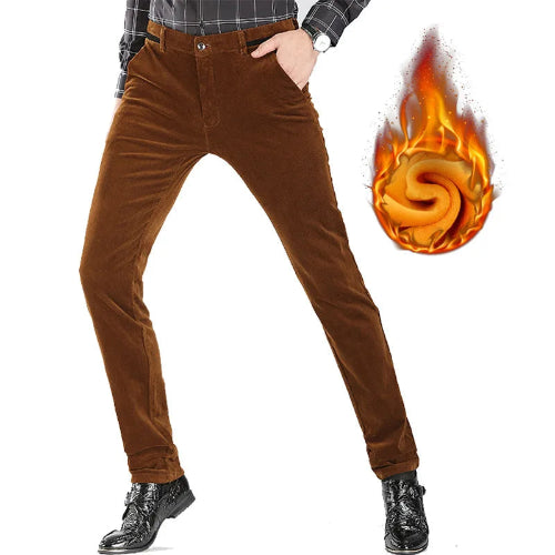Brown corduroy pants shown on a cropped model from the waist down, with a plaid shirt and black boots visible. A flame-and-wool graphic appears at the upper right to suggest warmth.