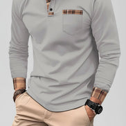 Man wearing a gray long-sleeve polo shirt with plaid accents on a city street.