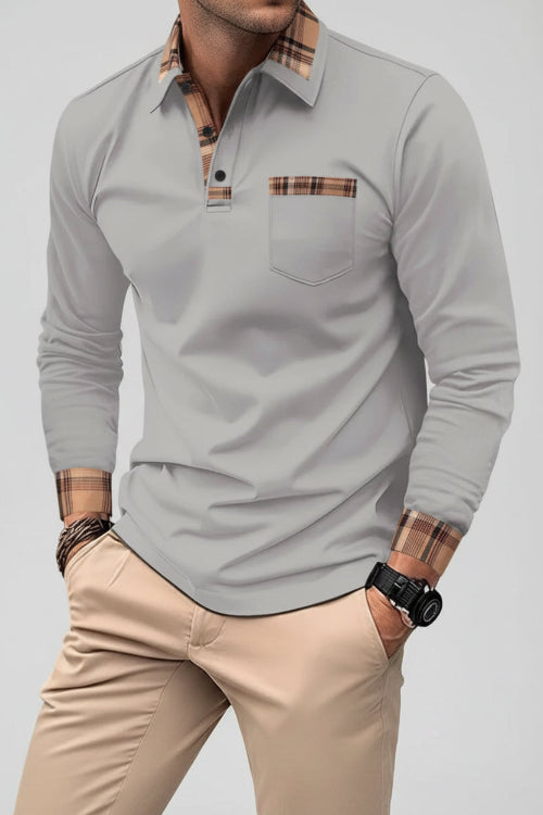 Man wearing a gray long-sleeve polo shirt with plaid accents on a city street.