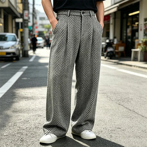 Gray herringbone wide-leg pleated pants worn by a man standing on a street