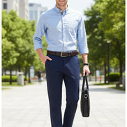 Person wearing navy blue dress pants with a brown belt and shoes, holding a black leather bag on a light gray background.