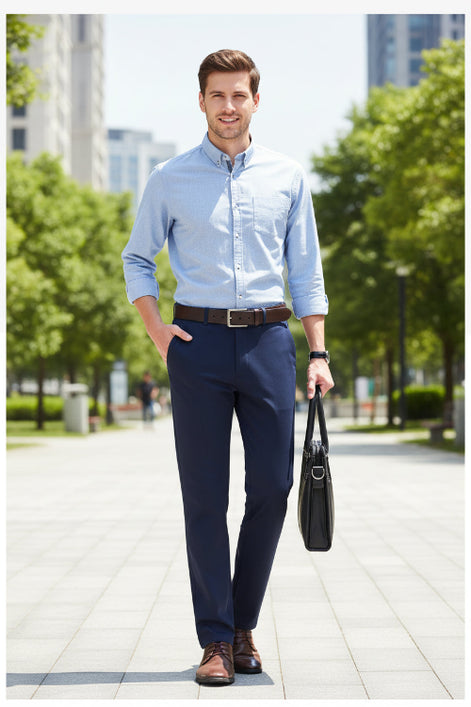 Person wearing navy blue dress pants with a brown belt and shoes, holding a black leather bag on a light gray background.