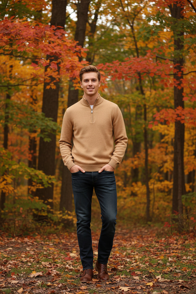 Folded beige sweater on a gray surface with a watch beside it
