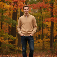 Folded beige sweater on a gray surface with a watch beside it
