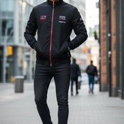 A black zip-up jacket with a high collar, featuring multiple graphic patches and logos on the front and sleeves, displayed on a white background with a TACE&SHARK 