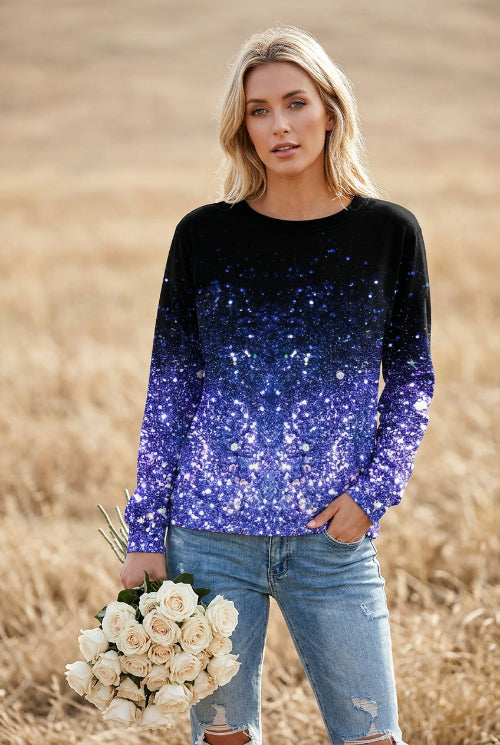 A woman wearing a long-sleeve crewneck top covered in sequins that fade from black at the top to bright blue and purple at the bottom, paired with distressed blue jeans 