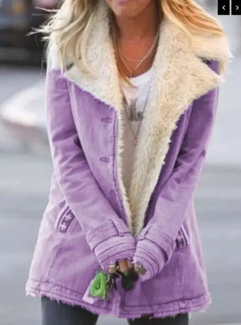 Woman outdoors wearing a purple coat with wide cream fleece-look lapels, front pockets and cuff tabs over a white top