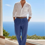 Person wearing blue pants with a brown belt, standing by a window with a scenic view.