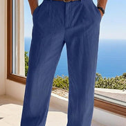 Person wearing blue pants with a brown belt, standing by a window with a scenic view.