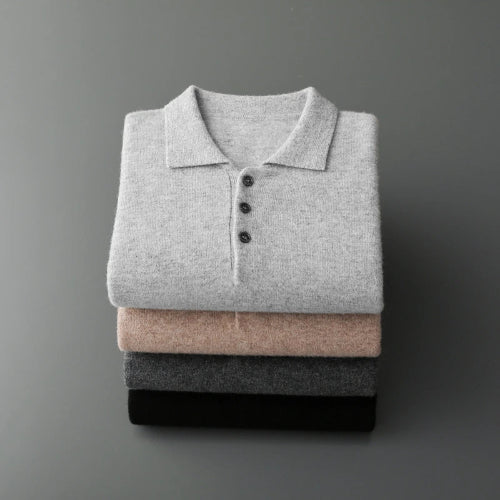A stack of four folded knit polo shirts in light gray, blush pink, charcoal gray, and black, arranged vertically on a dark gray background.