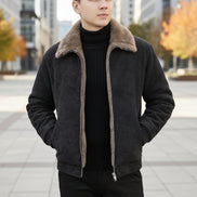 A man wearing a dark gray faux-suede jacket with a brown sherpa lining, opening the jacket to show the warm interior. A graphic of a burning flame is shown in the bottom right corner.