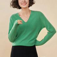 Woman wearing a green cashmere sweater with a beige background