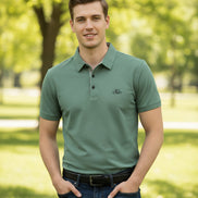 Green polo shirt on a hanger with a hand touching it, brand label visible