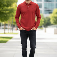 Red long-sleeve polo shirt with a brand logo on a rack with other colored shirts.