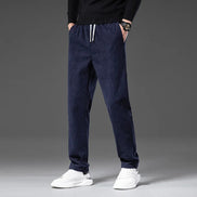 Person wearing navy blue jogger pants with white sneakers on a gray background