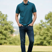 Green polo shirt with brand logo held by a hand on a gray background