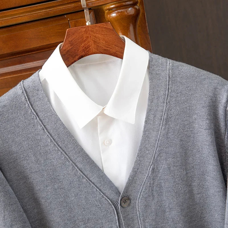 Gray cardigan over a white shirt on a wooden hanger against a wooden door background