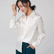 White silk shirt worn by a model with dark green trousers.