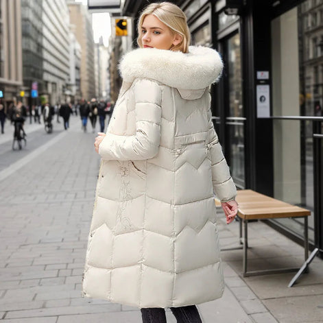 Woman wearing a long white puffer coat with a fur-lined hood on a city street.