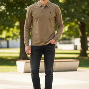 Brown long-sleeve polo shirt with Ralph Lauren logo on a hanger against a background of other colored shirts.